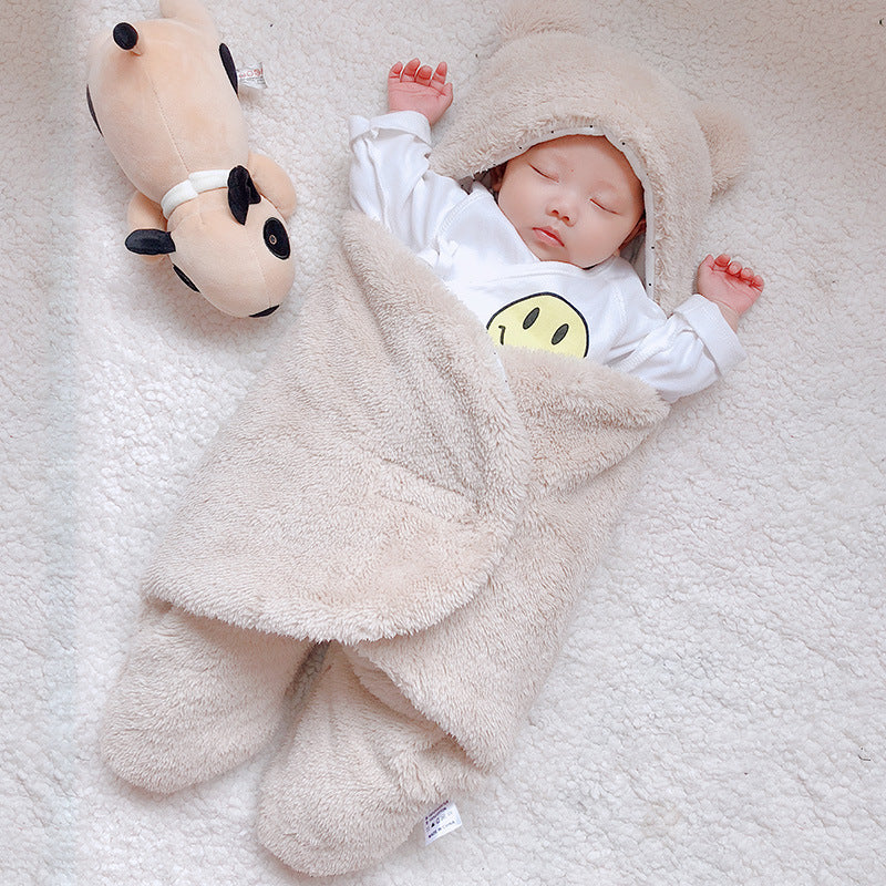 Baby i beige sovpåse med björnöron